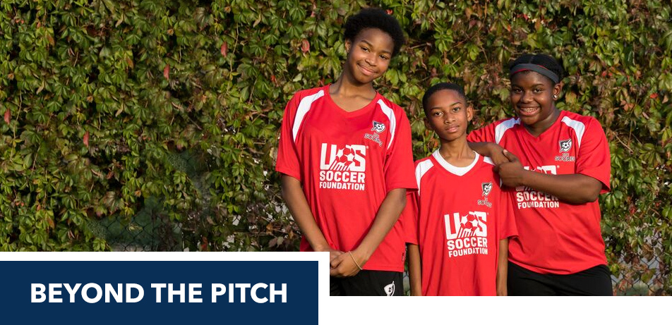 two girls and one boy posing in red soccer jerseys